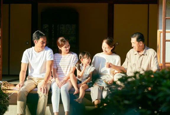 一家人坐在屋外共享時光,長輩與父母陪伴小孩聊天,象徵下班後的生活保持平衡的重要性。